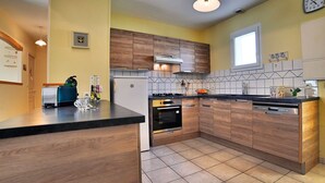 A modern kitchen with wooden cabinets, a black countertop, and a tiled floor.