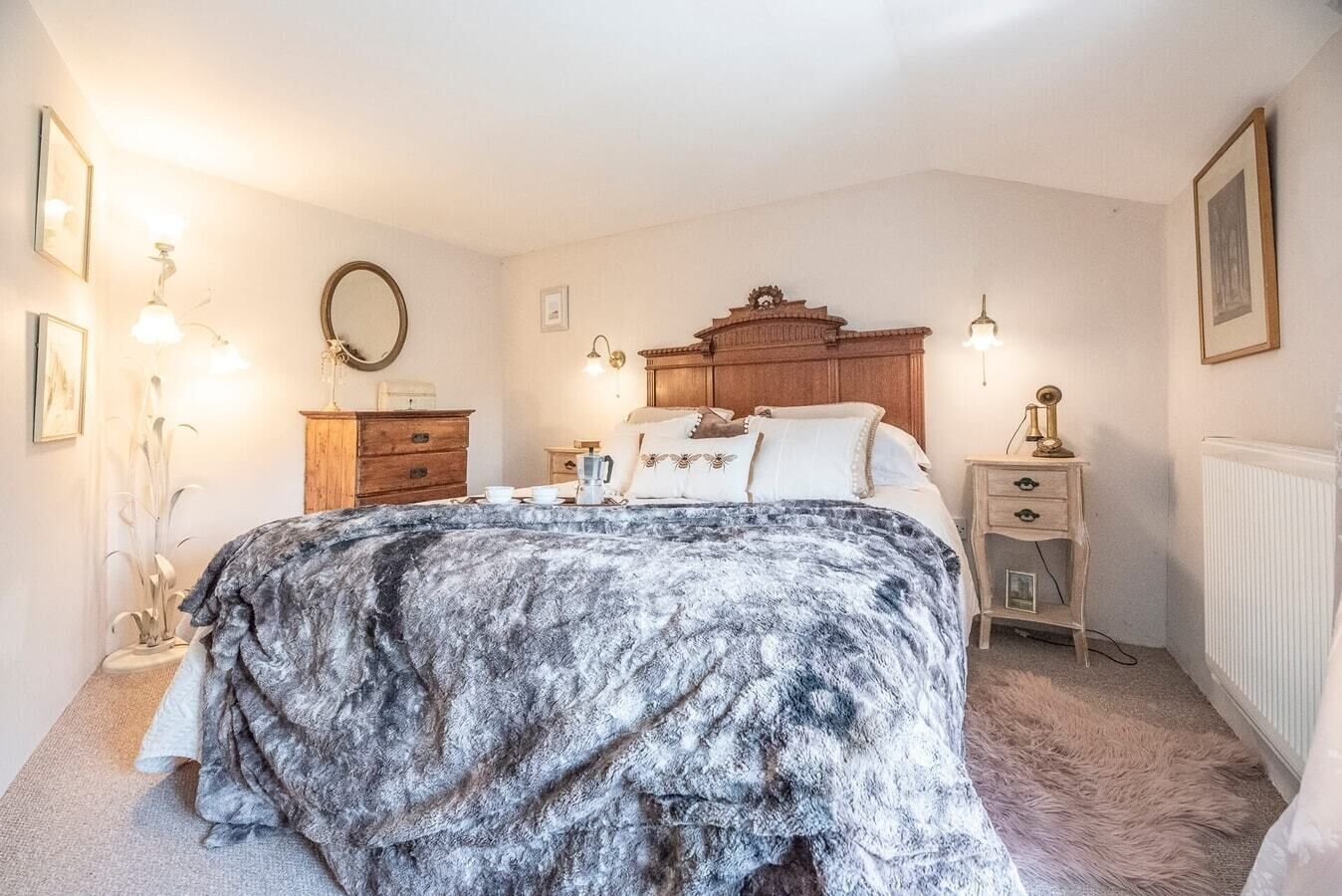 Un dormitorio con una cama grande, cabecera de madera, mesitas de noche y lámparas de pared.