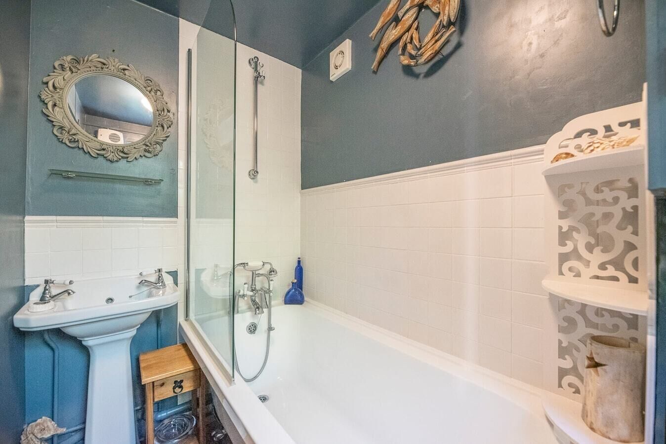 Une salle de bain avec un lavabo blanc, une douche à parois de verre et une baignoire blanche.