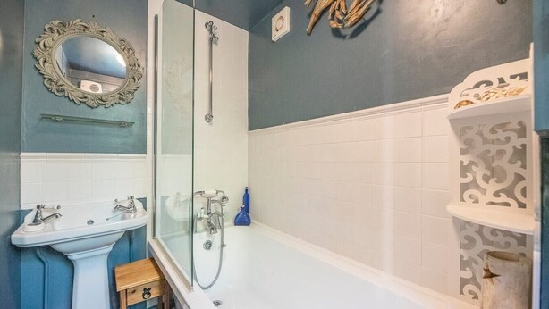Une salle de bain avec un lavabo blanc, une douche à parois de verre et une baignoire blanche.