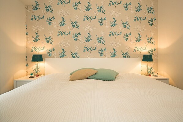 Un dormitorio con una cama grande, dos lámparas de noche y un estampado floral en el papel tapiz.