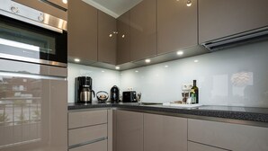 Cozinha moderna com eletrodomésticos embutidos, cafeteira e uma garrafa de vinho.