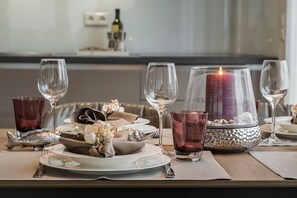 Una mesa de comedor dispuesta con platos, vasos y una vela.