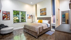 A bedroom with a large bed, a dresser, a chair, and artwork on the walls. - Sta-Haus | Wonderful Location (Fredericksburg)