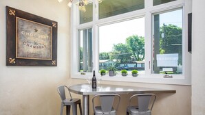A dining area with a table and three chairs, a bottle of wine, and a framed sign on the wall. - Sta-Haus | Wonderful Location (Fredericksburg)