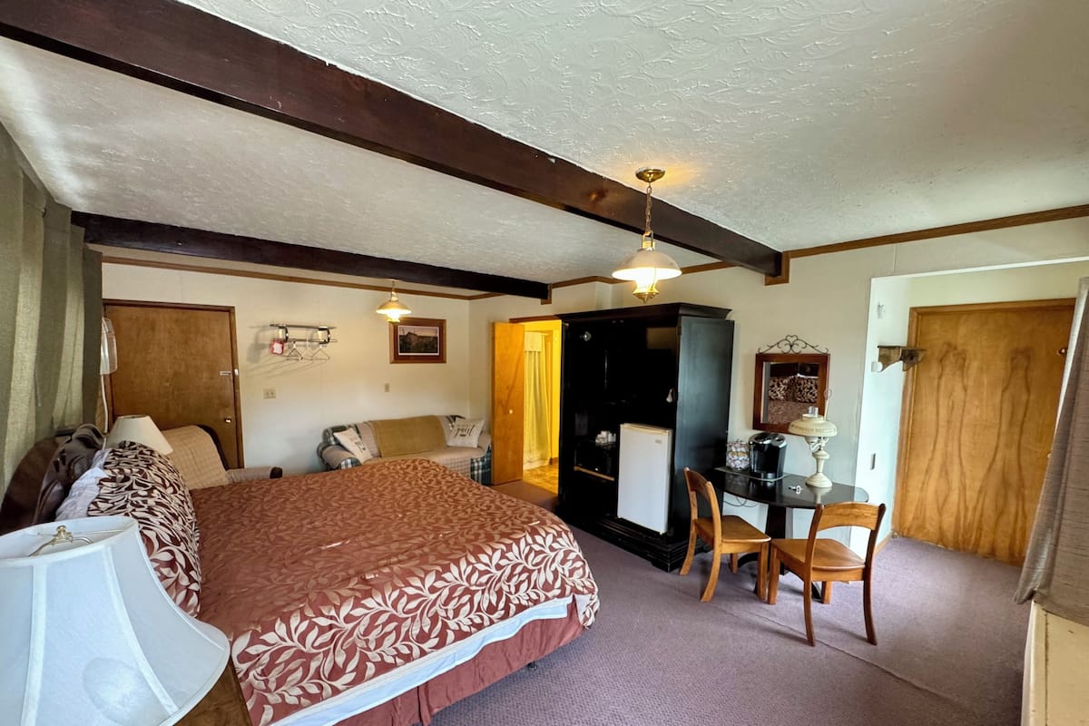 A bedroom with a bed, a desk, a chair, a wardrobe, and a ceiling fan.