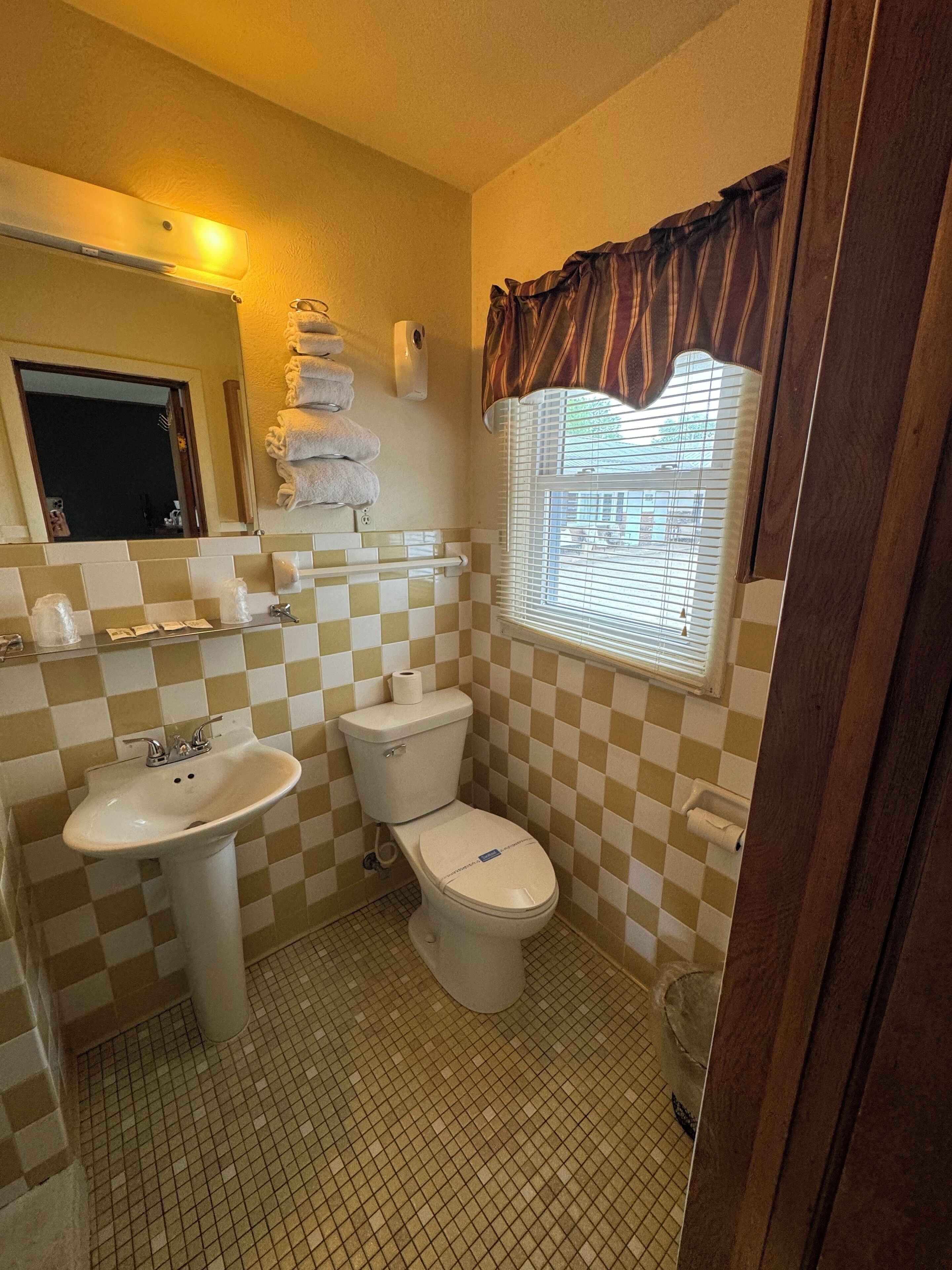 A bathroom with a sink, toilet, and a window with blinds.