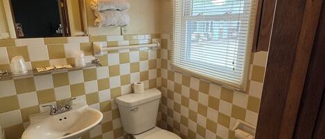 A bathroom with a sink, toilet, and a window with blinds.
