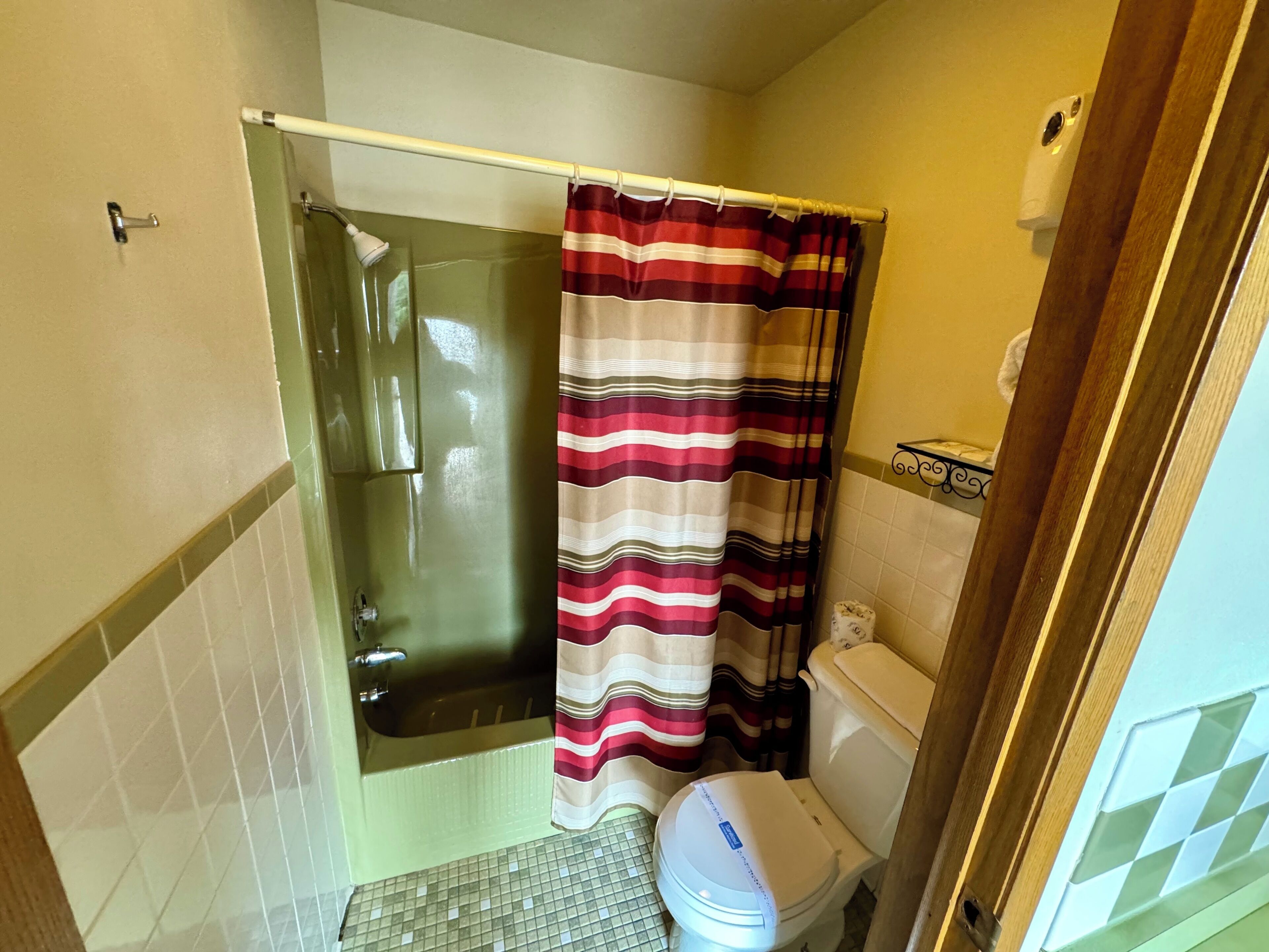 A bathroom with a glass shower enclosure, a toilet, and a striped shower curtain.