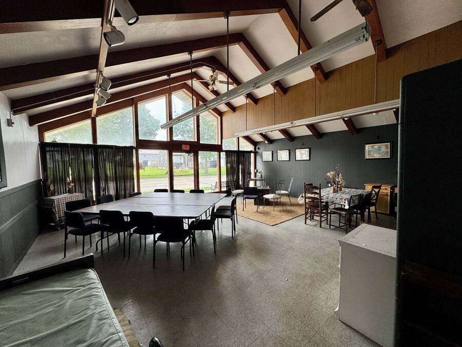 Um quarto espaçoso com uma mesa grande e cadeiras, uma pequena área de refeições e vista para o exterior através de amplas janelas.
