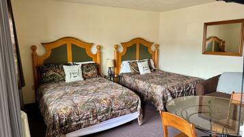 A hotel room with two beds, a glass table, and a chair.