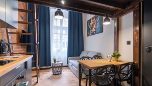 Ein gemütliches Zimmer mit Holztisch, Stühlen, einer Couch und einem kleinen runden Tisch mit Pflanze.