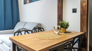 Ein Essbereich mit einem Holztisch, zwei herzförmigen Untersetzern, einem kleinen Topfpflänzchen und einem Bild an der Wand.