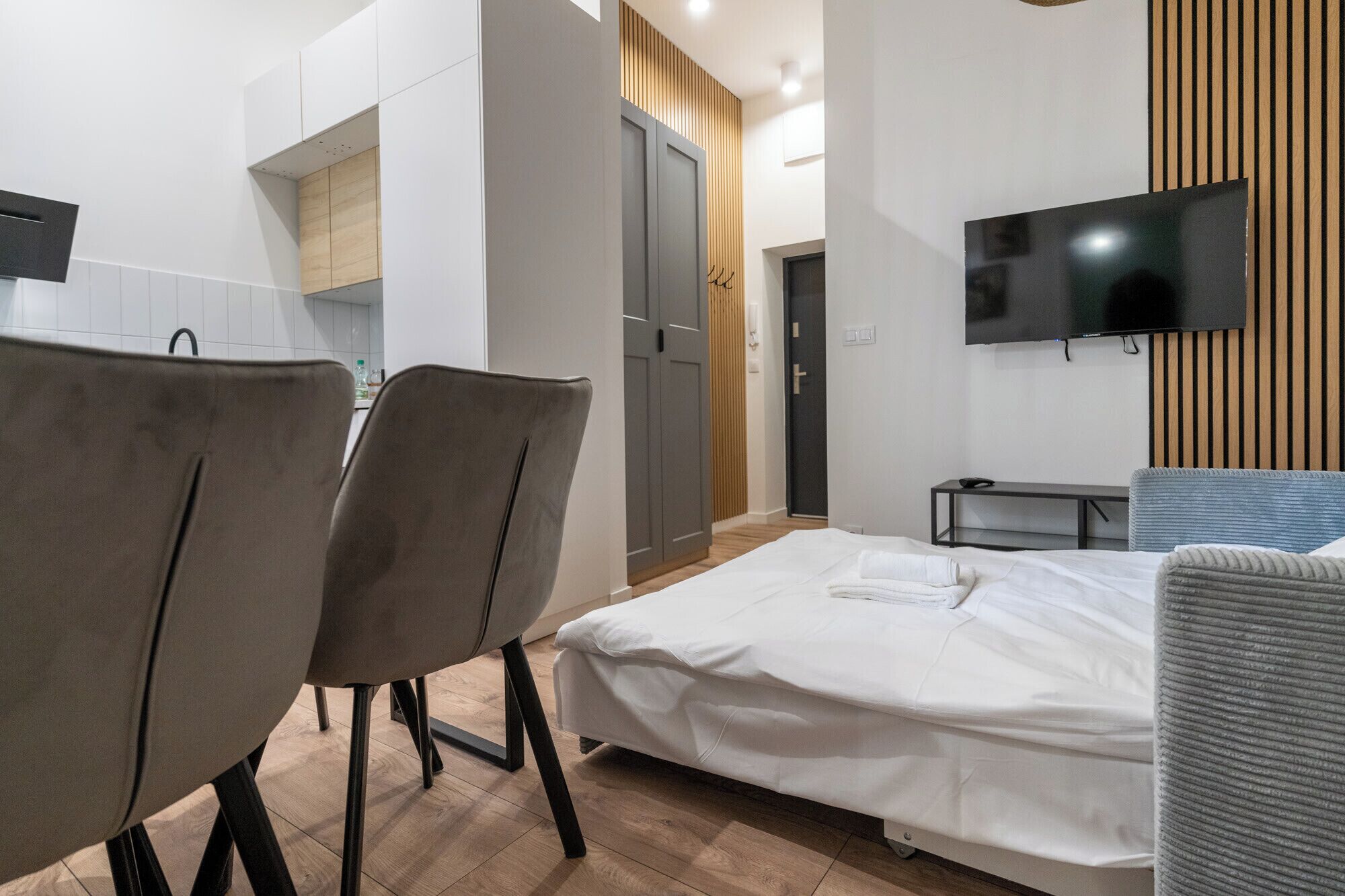 A modern hotel room with a bed, a TV, a desk, and a chair.