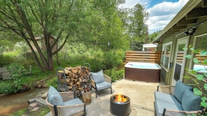 An outdoor patio with wicker furniture, a fire pit, and a hot tub.
