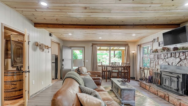 A spacious living room with a leather sofa, a stone fireplace, and a dining area with wooden chairs.
