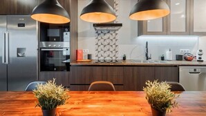 Une cuisine moderne avec des meubles en bois foncé, des appareils électroménagers en acier inoxydable et des luminaires suspendus.