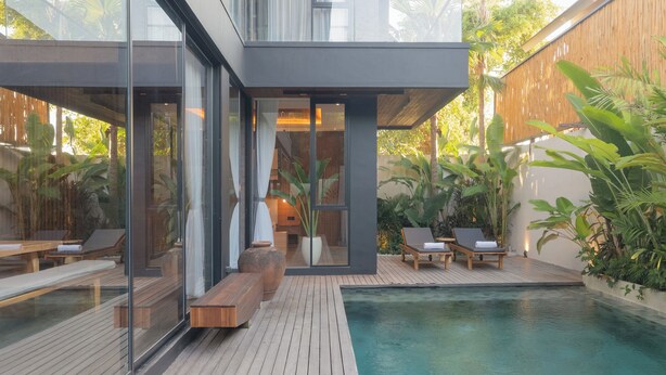 A modern house with a wooden deck, a swimming pool, and outdoor seating.