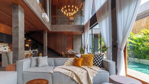 A modern living room with a grey sectional sofa, wooden coffee table, and a view of an outdoor pool.