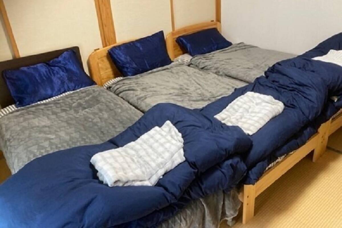 Une chambre avec un lit, une tête de lit en bois et un petit tabouret.