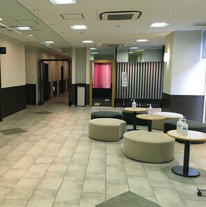 Um hall de hotel com piso de azulejos, áreas de estar e um balcão de recepção.