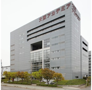 A modern building with a large glass facade, multiple floors, and a prominent entrance.