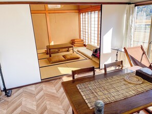 Una habitación japonesa tradicional con suelo de tatami, una mesa baja y un sofá con cojines.