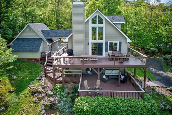 A two-story house with a deck, a covered patio, and a large window.