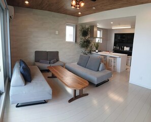 A modern living room with a sofa, a bench, and a kitchen in the background.