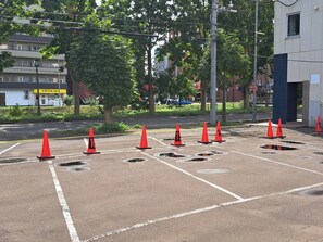 Park your vehicle in designated spaces, surrounded by trees and a nearby building with a food service sign.