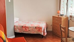 A compact room with a bed, a wooden dresser, a chair, and a small table. - Moschettieri by Interhome (Bibione)