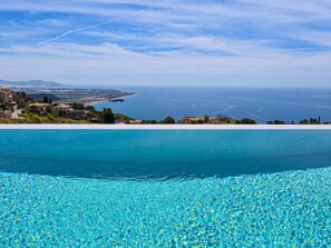 A clear view of a swimming pool with a view of the sea and distant coastline.