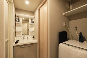 A modern bathroom with a white sink, mirror, and a built-in washing machine.