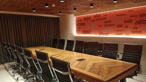 A conference room with a long wooden table, black chairs, and a word cloud on the wall. - Sapphire Boutique Hotel (Navi Mumbai)