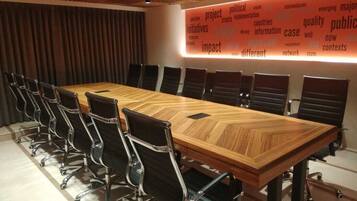 A conference room with a long wooden table, black chairs, and a word cloud on the wall.