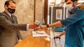 A hotel reception desk with a wooden counter and a marble wall in the background. - Sapphire Boutique Hotel (Navi Mumbai)
