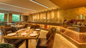 A modern dining area with a long counter, multiple seating options, and a buffet setup. - Sapphire Boutique Hotel (Navi Mumbai)
