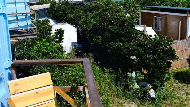 A deck with wooden chairs overlooking a beach and a clear blue sky. - The Reef (Lyudao)