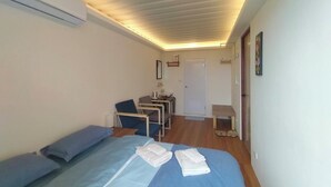 A bedroom with a bed, a desk, and a chair. There is a door and a small table with a chair. - The Reef (Lyudao)