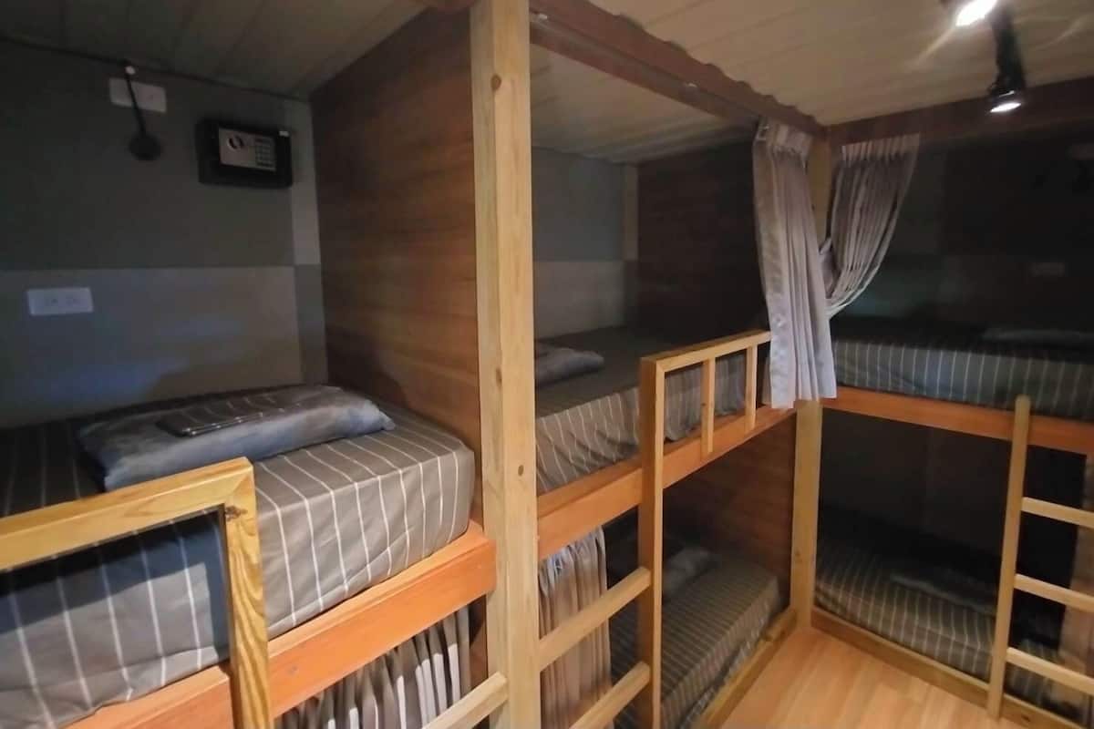 Quarto com beliches, paredes de madeira e ventilador de teto.