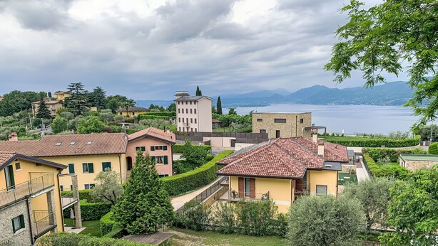 Un quartiere residenziale con case, una piscina e vista su un lago e montagne.