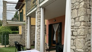 Un'area patio con tavolo e sedie, muri in pietra e un balcone.