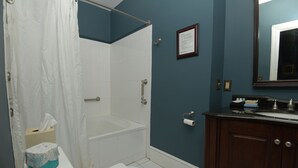 A bathroom with a bathtub, toilet, sink, and a framed certificate on the wall.