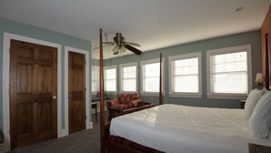 A bedroom with a four-poster bed, a ceiling fan, and a window with blinds.