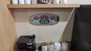 Ein Kaffee-Bereich mit einer Keurig-Maschine, einer Kaffeetasse, einem Teebehälter und mehreren kleinen Gläsern.