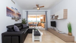 Un saló modern amb un sofà modular, una taula de centre, una televisió i un balcó amb vistes.