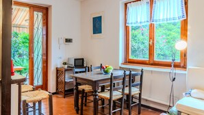 A dining area with a wooden table and chairs, a small television, and a window with curtains. - Apartment Mofra by Interhome (Bellano)