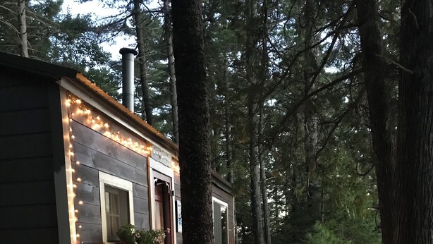A cabin with a deck, string lights, and potted plants. - Historic 1940s lakeside cabin on  spring-fed pond. Close to Acadia National Park (Franklin)