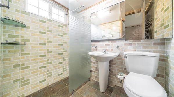 A bathroom with a glass shower enclosure, a pedestal sink, and a toilet.
