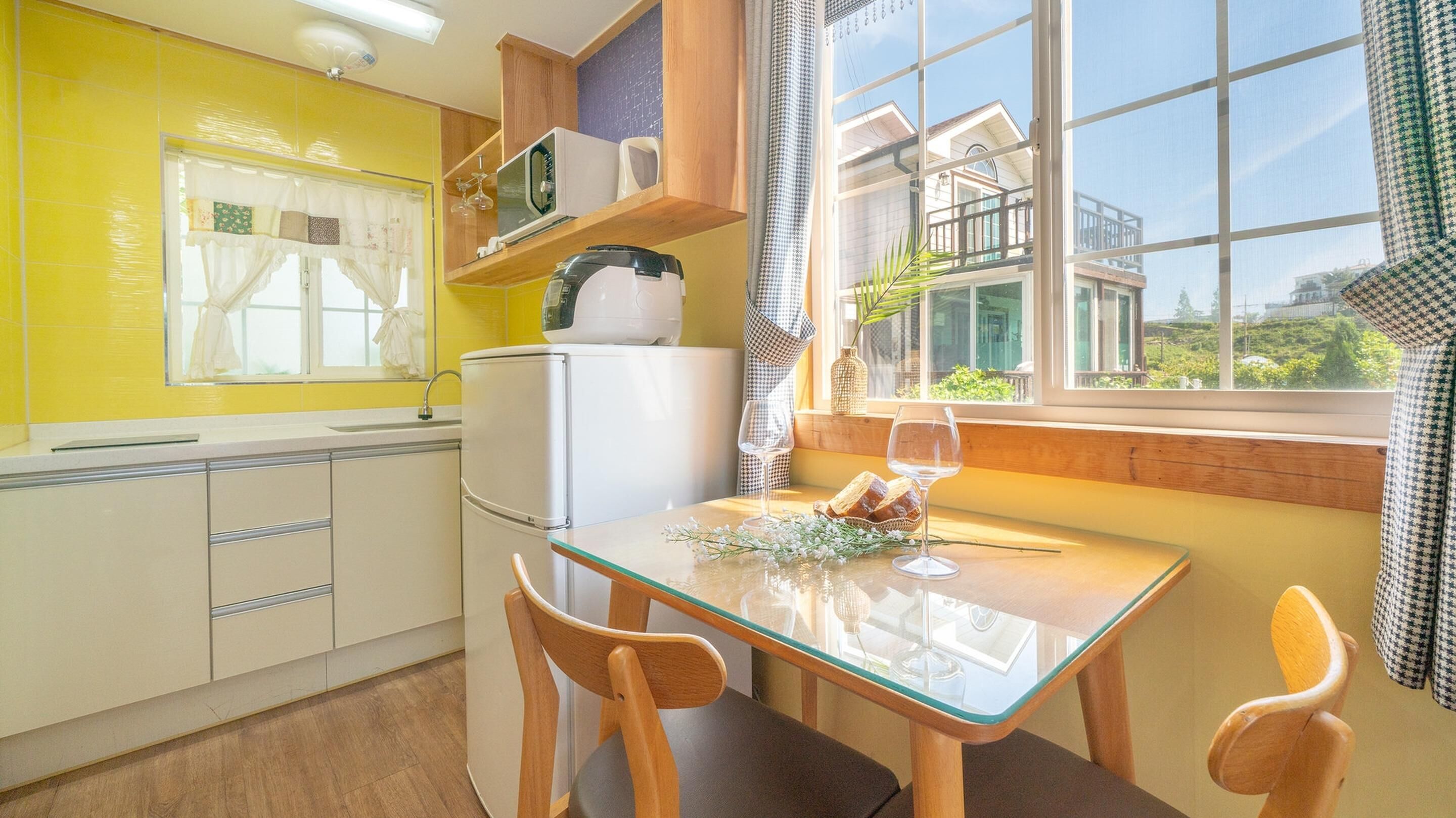 A kitchen with yellow walls, a refrigerator, a microwave, and a dining table with chairs.